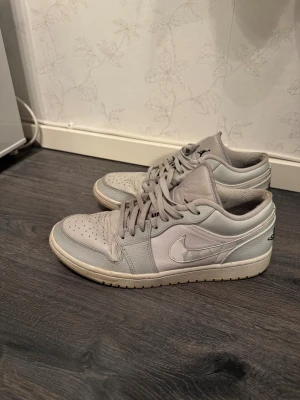 Nike Air Jordan 1 Low i grått - Nike Air Jordan 1 Low sneakers i ljusgrå och vit färg. Storlek 45. Välanvända.
