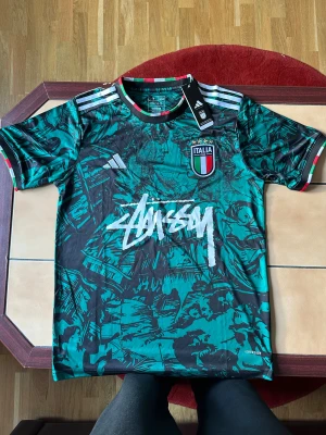 Italien x Adidas x Stüssy edition. Strl. M - Grön Italien x Stüssy tröja i storlek M med ett fint Rom motiv 