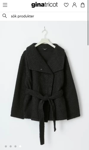 Svart teddyjacka med bälte Gina Tricot - Svart teddyjacka från Gina Tricot med bred krage och knytbälte i midjan. Jackan har lång ärm och en mjuk, fluffig yta som ger en chill vibe. Perfekt för dig som gillar oversized look och vill ha något varmt och snyggt till höst och vinter.