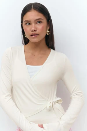 Vit tröja med knyt - Superfin lite kräm vit omlottopp från Gina Tricot med lång ärm och knyt i sidan. Tunn och mjuk i materialet, perfekt att styla över ett linne eller topp. V-ringad och croppad modell som ger en trendig look. Storlek 158/164 passar som xs