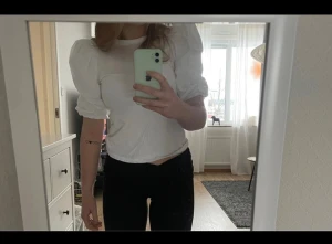 Vit puffärm blus från H&M XS - Säljer en vit blus från H&M i storlek XS med puffiga korta ärmar och rund hals. Toppen är gjord i mjuk bomull och har en clean, stilren look som är lätt att matcha. 🥰