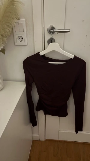 Vinröd långärmad topp med öppen rygg - Säljer en vinröd långärmad topp från Gina med en snygg öppen rygg. Toppen har en tight passform och är tillverkad i mjuk polyester. Perfekt för dig som vill ha en stilren och trendig look med en twist på ryggen.