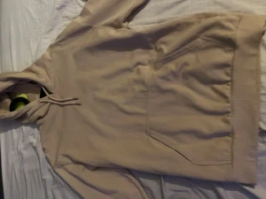 Beige hoodie från 157 med huva - Säljer en beige hoodie från 157 i storlek S. Tröjan har en stor magficka, snörning vid huvan och ribbade muddar vid ärmslut och nederkant. Perfekt för chill dagar och enkel att matcha med jeans eller mjukisbyxor.
