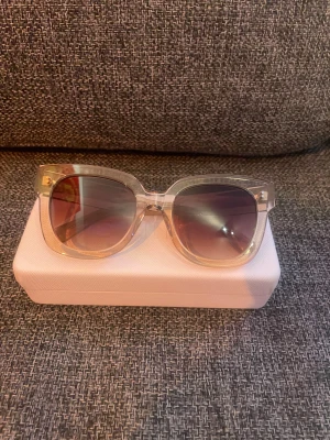 Transparenta CHIMI solglasögon - Snygga solglasögon från CHIMI med transparent, fyrkantig båge i plast och gradienttonade linser som går från mörkgrå till ljusare nyans. Kommer med vit CHIMI-fodral. Perfekt accessoar för att lyfta din stil.