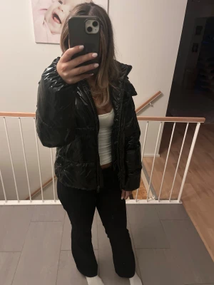 Svart pufferjacka från Nelly - Säljer en svart, glansig pufferjacka från Nelly med huva och dragkedja framtill. Köpte förra vintern men har nästan aldrig kommit till användning💗slutsåld, kan tänka mig gå ner i pris vid snabb affär