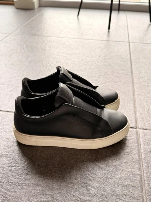 Axel arigato skor  - Säljer mina arigato skor då de tyvärr inte kommer till någon användning längre. Skorna är väldigt fina i sig med få skavanker. Kolla noggrant på bilderna för att se skavankerna. Men det är inget man märker när man har på sig skorna. Använd få gånger. Nypris 2800 säljer för 1350. Pris går att diskutera. Lådan till skorna tillkommer samt påsen. Är i storlek 37 men jag är oftast en 38/37,5 och de passar mig. 