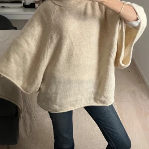 Beige stickad ponchotröja med polokrage - Supermysig beige stickad ponchotröja med polokrage och vida ärmar.