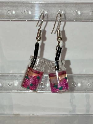 Örhängen  -  Handgjorda örhängen som görs av mig. Med lila frukter i ett glas. Frakten är ca 22-100kr beroende på vikten på produkten . Kontakta mig om du vill köpa.