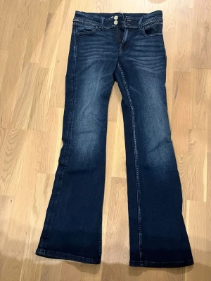 Mörkblå bootcut jeans Gina Tricot - Säljer ett par mörkblå bootcut jeans från Gina Tricot i storlek 164. Jeansen har klassisk femficksmodell, dubbla knappar i midjan och snygga sömmar på bakfickorna. Materialet är jeans med lätt tvättade detaljer för en cool look. (ALDIG ANVÄNDA)