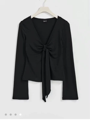 Långärmad knyt topp GinaTricot  - Säljer min långärmade svarta topp från Gina Tricot i storlek XS. Den har band framtill som man knyter, och en v-ringning. Inte använd mycket. Köpt för 300.