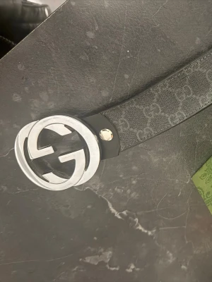 Svart bälte - Säljer ett svart Gucci bälte med klassiskt GG-mönster och stort silverfärgat GG-spänne. Bältet har en stilren design och är tillverkat i slitstarkt material med exklusiv känsla. Perfekt accessoar för att lyfta vilken outfit som helst.