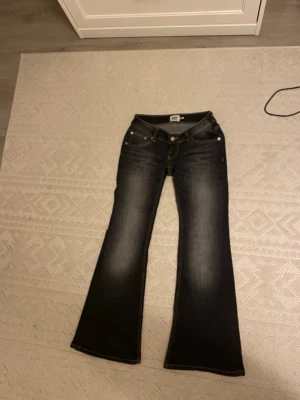 Flare jeans från 157, mörkblå, M - Flare jeans från 157 i mörkblå tvätt med snygga slitningar framtill. Klassisk femficksmodell med kontrastsömmar och låg midja. Jeansen är i stretchigt denim och har en riktigt schysst passform som ger en retrovibe. Båda sidor är sy så att de inte åker ner och behöver kunna dra upp hela tiden. Helt ny och anledningen är längden och kan inte returnera 