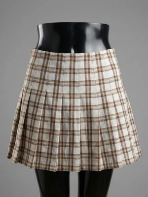 Brun och vit rutig kortkjol från H&M - Säljer en brun och vit rutig kortkjol från H&M Divided i storlek 34. Kjolen har plisserad design och är gjord av 98% polyester och 2% elastan, vilket gör den mjuk och bekväm. Perfekt för dig som gillar preppy stil och vill ha något snyggt till garderoben.