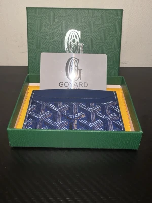 Blå Gplånbok med mönster - Blå g-plånbok med elegant mönster i snyggt texturerat material. Rymlig och praktisk med flera fack för kort, sedlar och mynt. Stilren och trendig design som passar både vardag och fest. Plånboken är i gott skick och ett perfekt tillbehör för dig som vill kombinera funktion med mode.