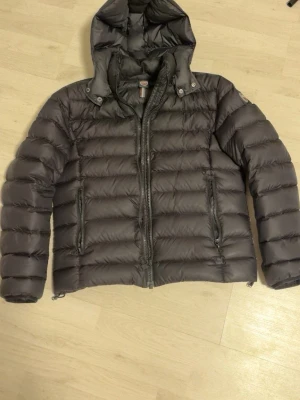 Svart dunjacka från Colmar - Säljer en svart dunjacka från Colmar med huva och två dragkedjeförsedda fickor. Jackan har en quiltad design och är perfekt för kalla dagar. Klassisk Colmar-logga på ärmen och hel dragkedja framtill. Snygg och enkel modell som funkar till det mesta.