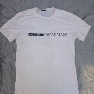 Vit Emporio Armani t-shirt  - Vit t-shirt från Emporio Armani i storlek L  men sitter som S, klassisk rund hals och svart logotyptryck över bröstet. Enkel och stilren design, perfekt för dig som gillar exklusiva märken och en clean look. Skriv för frågor, bilder och offer ✅