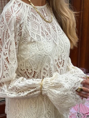 Lace Bow Blouse -  - Spetstyg utan stretch. - Rak passform. - Rund halsringning. - Djup rygg med knytband i nacken. - Raglanärmar med volang vid ärmsluten. - Längd från axel: 56 cm i storlek S.