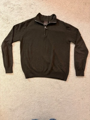 Mörk grön half zip tröja Oscar Jacobson XS - Mörk, stilren svart tröja från Oscar Jacobson i storlek XS. Tröjan har en klassisk half zip-dragkedja och hög krage. Tillverkad i Italien och gjord i ett mjukt, stickat material som passar perfekt till kyligare dagar.