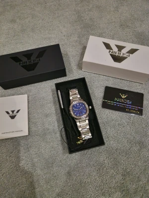 Nibosi klocka - En Nibosi klocka. Aldrig använd samt i jätte fint skick. Man får med lite saker som man kan se på bilden