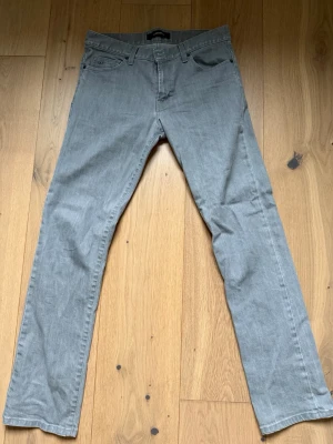 Grå J.Lindeberg jeans - Snygga grå J.Lindeberg jeans med klassisk femficksdesign och med diskret logga på myntfickan. Jeansen har en rak passform och är tillverkade i mjukt denim-material. W31 L32 Ny pris ligger på runt 1099KR Priset kan diskuteras vid en snabb affär