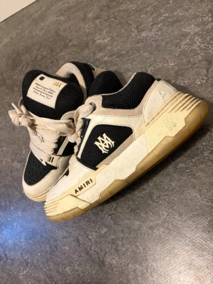 Svarta och vita sneakers från Amiri - Säljer ett par feta Amiri sneakers i svart och vitt med grova snören och meshdetaljer. Skorna har tydlig Amiri-logga på sidan och cool kontrast mellan svart mesh och vita skinnpaneler. Sulan är beige och har en chunky look. Perfekta för dig som vill sticka ut. (Boxen ingår)