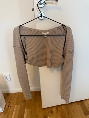 Bolero  - Säljer en beige croppad stickad bolero med ribbad struktur och långa ärmar. Perfekt till hösten eller våren och superenkel att styla med både jeans och kjol. Tröjan har en loose fit och känns riktigt trendig.
