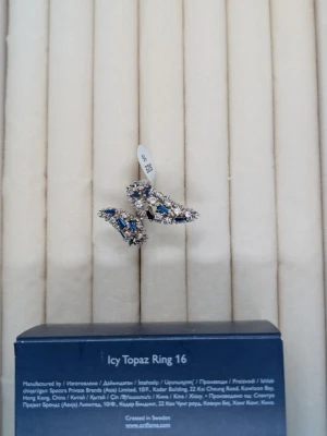 Ingen väst på bilderna - Bilderna visar ingen väst utan ett smycke, troligen en ring med blå och klara stenar samt en blå påse. Ingen väst kan beskrivas.