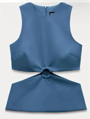 Trendig blå cut out topp från Zara - Säljer en trendig  blå topp från Zara med cool ringdetalj framtill och cut-out i midjan. 