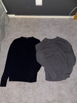 Två basic stickade tröjor  - Går även att köpa dessa tröjor i packet för bättre pris. Går att köpa separat. Säljer två stilrena stickade tröjor en i mörkblått och en i grått. Båda har rund halsringning och lång ärm, perfekta för lager på lager under höst och vinter. Materialet är mjukt och följsamt, storlek Xs