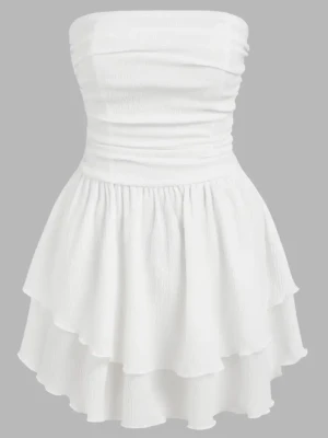 Vit axelbandslös kortklänning - Supersöt vit kortklänning med volangkjol och smockad överdel. Axelbandslös design som ger en clean och fräsch look, perfekt för varma dagar. Klänningen har dubbla lager i kjolen för extra volym och flow. Perfekt för student eller liknande