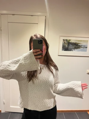 Ljus stickad tröja med vida ärmar - Supermysig ljus stickad tröja med breda, långa ärmar och avslappnad passform. Perfekt att slänga på sig när det är kyligt ute. Tröjan har en grovstickad struktur och är enkel att matcha med jeans eller kjol.