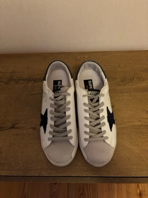 Golden goose skor - Jag har ett par i 42 och 43. Golden Goose skor som är i väldigt bra kvalitet med nya skosnören och nya sulor, de är väldigt snygga och har mörkblått där bak och en mörkblå stjärna 