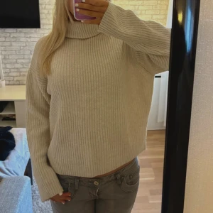 Beige ribbad polotröja  - Säljer en beige stickad polotröja med ribbad struktur. Tröjan har lång ärm och en hög krage som ger en chill och mysig vibe. Perfekt för att hålla sig varm och ändå se snygg ut under hösten och vintern.