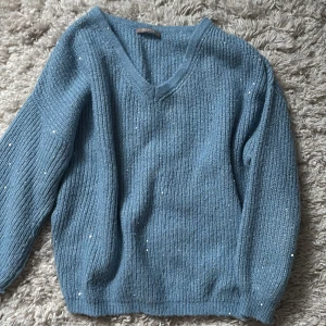Ljusblå stickad tröja med paljetter - Mysig blå stickad tröja med v-ringning, långa ärmar och små paljetter över hela tröjan✨Aningen för liten på mig som brukar ha M på stickade tröjor, passar bäst för dig som har XS/S 💕