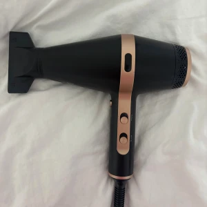 Rusta Hårfön 2200W - Elegant svart och rosé guld hårfön från Rusta med maxeffekt på 2200W. Utrustad med flera värme- och hastighetsinställningar. Produkten är i mycket gott skick utan synligt slitage eller defekter.