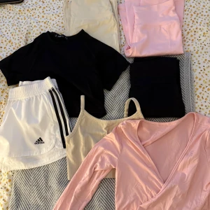 Träningskläder  - Blandade träningskläder: Två par bootcut leggings, ett par rosa och ett par beiga. Ett par svarta ribbade tights. En rosa topp med snörning. En svart kortärmad cropped topp. En beige träningstopp och ett par vita shorts från Adidas. Flera av plaggen är i nytt skick✨Vill mest bli av med grejerna då de inte kommer till användning😊hör av dig om du vill se fler bilder på något! (80:- för alltihop) 