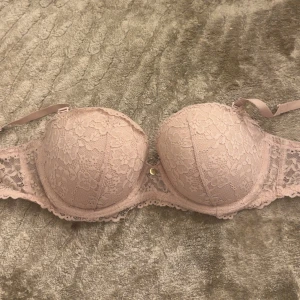 Beige spets korsett från H&M 80C - Säljer en beige korsett från H&M i storlek 80C. Den har vacker spets med blommigt mönster och formade kupor. Axelbanden är justerbara och det finns en liten guldfärgad detalj mellan kuporna. Perfekt för dig som gillar romantisk stil. Priset kan diskuteras