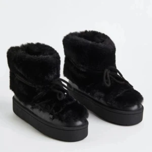 Svarta fluffiga moon boots med platå - Säljer ett par svarta inspererade moon boots med fluffig pälsimitation och snörning framtill. Skorna har en rejäl plattformsula som ger extra höjd och en rund tå. Perfekta för vintern när du vill ha både värme och stil.- dessvärrre slutsålda!! 