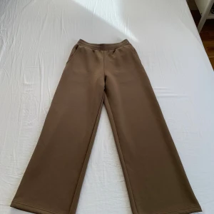 Oanvända Bruna wide mjukisbyxor från Uniqlo - Oanvända Bruna mjukisbyxor med breda ben och resår i midjan. Byxorna har en enkel design med fickor på sidorna och en bakficka. Tillverkade i mjukt material som känns skönt mot huden och har en avslappnad passform. Lappen är avklippt, men byxorna har aldrig använts. Nytt pris: 399 kr.