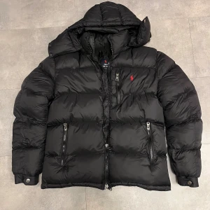 Svart pufferjacka från Polo Ralph Lauren - Svart pufferjacka från Polo Ralph Lauren. Jackan är i superfint skick. Storleken är L, juniorstorlek så den passar 12-14 åring, 158-164. 