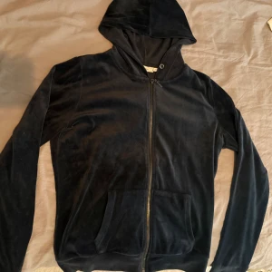 Marinblå velour hoodie från Zink - Marinblå hoodie från Zink i mjuk velour med dragkedja framtill och huva. Tröjan har långa ärmar och två fickor på framsidan. Snyggt och enkelt plagg som funkar året runt.