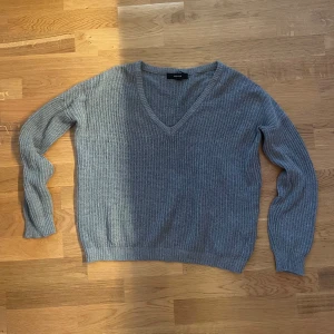 Grå ribbad stickad tröja V-ringad - Säljer en grå stickad tröja från Forever21 med ribbad struktur och snygg v-ringning. Tröjan har lång ärm och är perfekt för lager-på-lager. Enkel och stilren design som passar till det mesta.