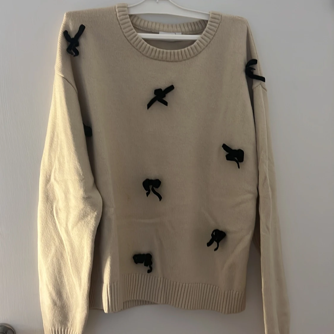 Beige stickad tröja med svarta rosetter