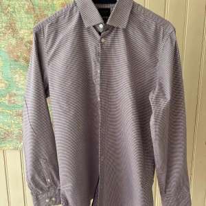 Rutig slim fit skjorta från Selected Homme - Snygg rutig skjorta från Selected Homme i slim fit-modell. Skjortan har små rutor i rött, blått och vitt, klassisk krage och långa ärmar med knappar vid manschetterna. Tillverkad av ekologisk bomull och är lätt att stryka.