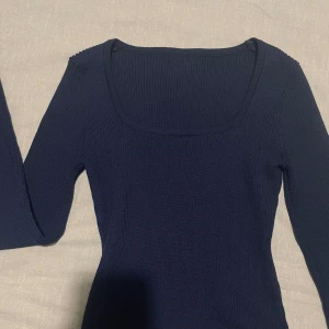Mörkblå ribbad stickad tröja - Snygg mörkblå stickad tröja med ribbad struktur och långärmad modell. Tröjan har en fyrkantig halsringning som ger en modern vibe och sitter figurnära. Helt ny, säljer då den ej kommit till användning💕