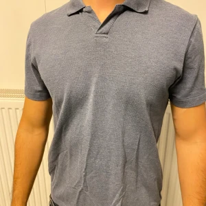 Blå pikétröja från Bläck - Säljer en stilren blå pikétröja från Bläck. Tröjan har klassisk krage, korta ärmar och är tillverkad i mjuk bomull.  Ny skick🌟 Storlek S🌟 Fraktar snabbt 🌟