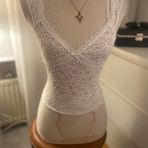 Vit spets linne - Säljer ett vackert vitt spetslinne med djup v-ringning och breda axelband. Linnet är helt i spets och har en romantisk känsla. Köpt tidigare från Plick, finns varken märke eller storlek men uppskattas att vara S/Xs❤️ märkena är ej på toppen utan på skyltdockan.