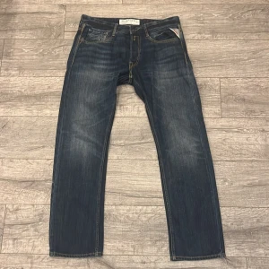 Replay jeans mörkblå denim - Snygga Replay jeans i mörkblå tvätt med klassiska fem fickor och kontrastsömmar. Jeansen har rak passform och normal midja, tillverkade i slitstark bomullsdenim. Perfekt för dig som gillar en tidlös och cool look. Jeansen är Storlek 33 och är tyvärr osäker på modellen eftersom de inte står, men jeansen sitter som ”regular fit” jeans
