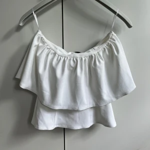 Vit volangtop  S - Helt ny. Superfin vit topp från Zara med dubbla volanger.  Toppen är ärmlös och har en luftig, flowy känsla som passar perfekt till varma dagar. 