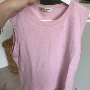 Ljusrosa ärmlös linnetopp Repeat - Supersöt ljusrosa linnetopp från Repeat i mjuk kashmir. Toppen är ärmlös med rund halsringning och har en clean, enkel design utan detaljer. Perfekt för dig som gillar en chill och stilren look. Materialet är lyxigt och känns skönt mot huden.